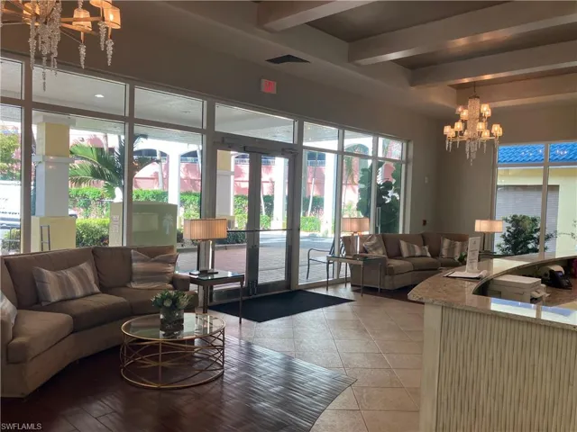 Grand entry foyer featuring an ornate chandelier, coffered ceilings, and expansive floor-to-ceiling windows