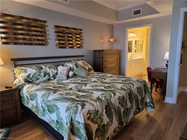 Bedroom featuring wood-finish flooring, crown molding, and a tray ceiling