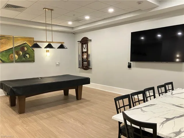 Recreation room featuring wood-finish flooring, recessed lighting, and a contemporary ceiling light fixture