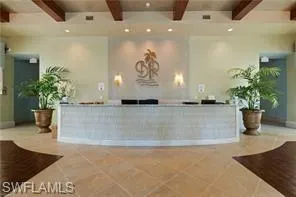 Expansive reception area featuring a curved front desk, recessed lighting, and decorative ceiling beams