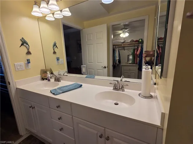 Dual sink vanity with white cabinetry and chrome fixtures, illuminated by a multi-bulb light fixture