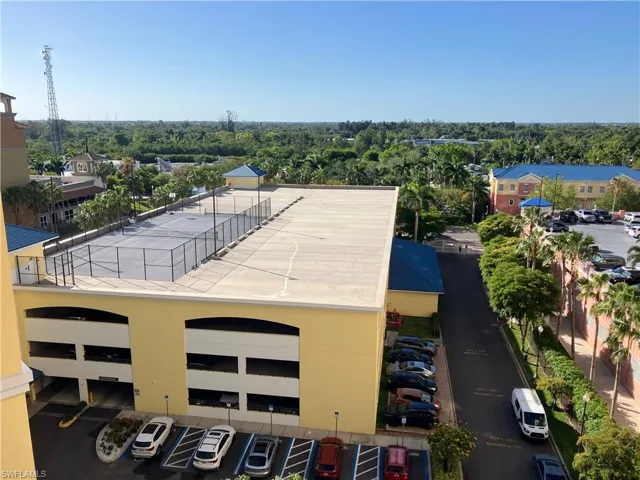 Rooftop court with surrounding fencing, adjacent to a multi-level parking structure