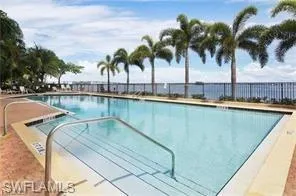 Resort-style swimming pool featuring a tanning ledge, stainless steel handrails, and a water feature