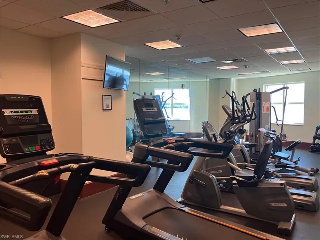 Fitness center with multiple cardio machines, mirrored walls, and recessed ceiling lighting