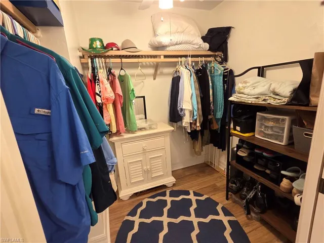 Recessed closet space featuring wood-finish flooring, built-in wooden shelving, and a wall-mounted clothing rod