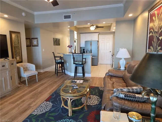 Open-concept living space featuring wood-finish flooring, recessed lighting, and crown molding