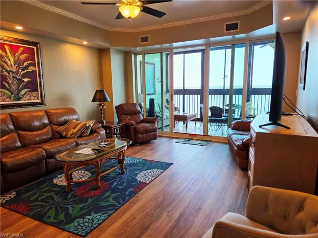 Living area featuring wood-finish flooring, recessed lighting, and crown molding