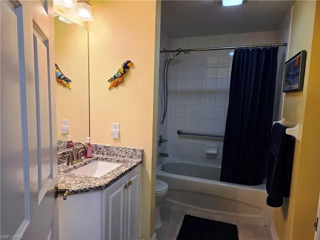 Bathroom featuring a white vanity with a granite-style countertop, undermount sink, and brushed nickel faucet
