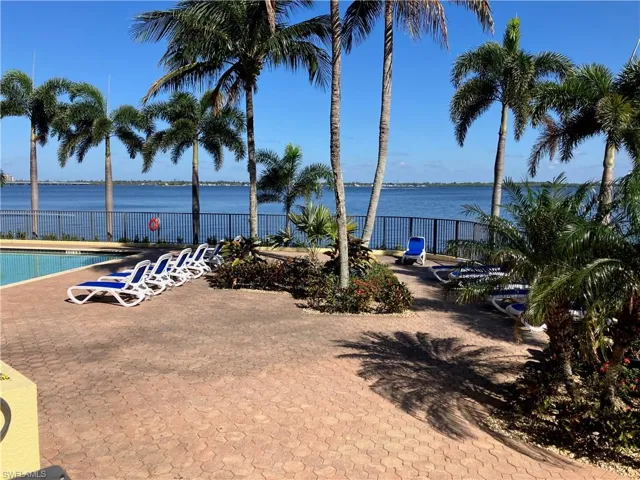 Waterfront paver patio featuring a swimming pool and tropical landscaping