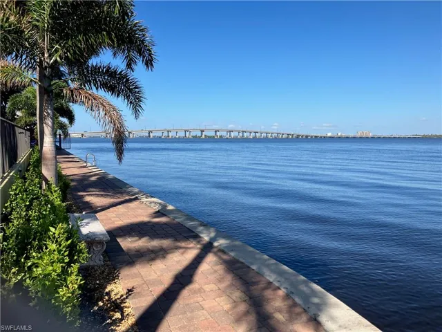 Waterfront brick paver walkway featuring mature palm trees and lush landscaping
