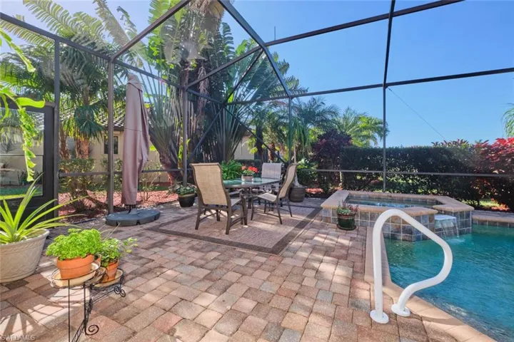 View of patio featuring screen enclosure and a pool with hot tub