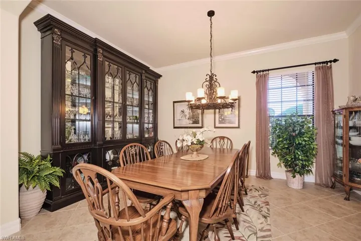 Tiled dining area featuring a notable chandelier and ornamental molding