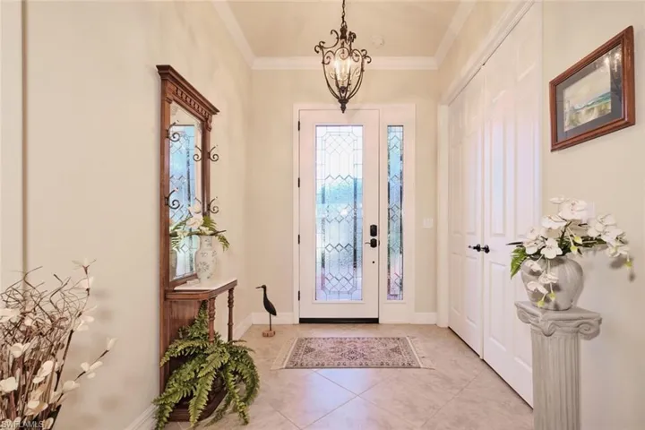 Entrance foyer featuring an inviting chandelier, ornamental molding, and light tile patterned flooring