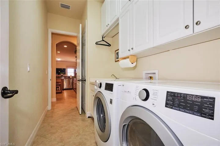 Clothes washing area featuring cabinets, light tile patterned floors, and separate washer and dryer