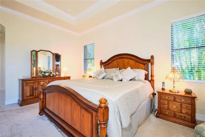 Carpeted bedroom with a raised ceiling and ornamental molding