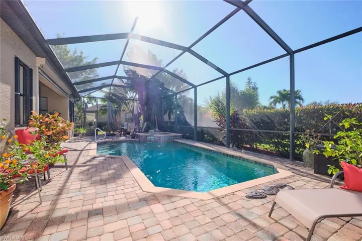 View of swimming pool with screen enclosure and a patio