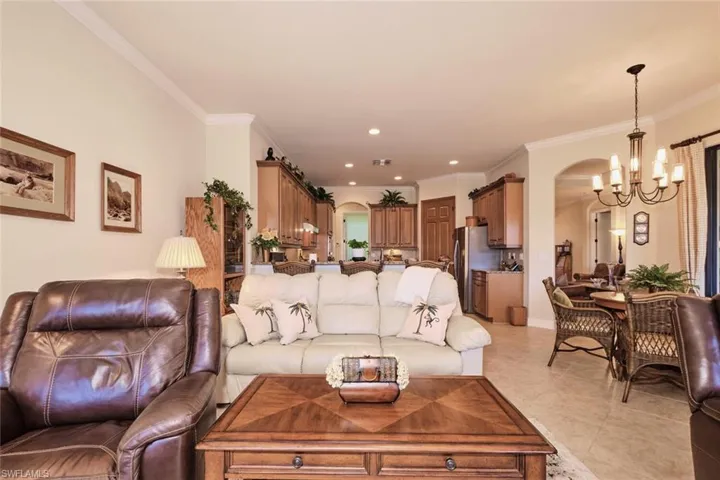 Living room featuring light tile patterned floors, ornamental molding, and a chandelier