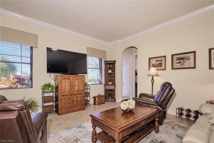Living room with a wealth of natural light, crown molding, and light tile patterned flooring