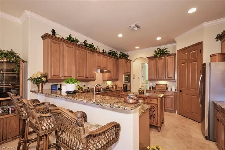 Kitchen with a kitchen breakfast bar, kitchen peninsula, dark stone counters, and stainless steel appliances