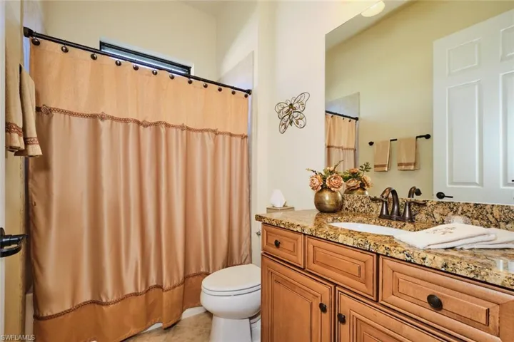 Full bathroom with tile patterned floors, vanity, toilet, and shower / tub combo with curtain