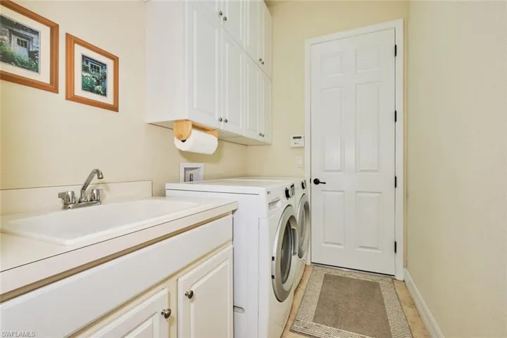 Laundry room featuring washer and clothes dryer, sink, and cabinets