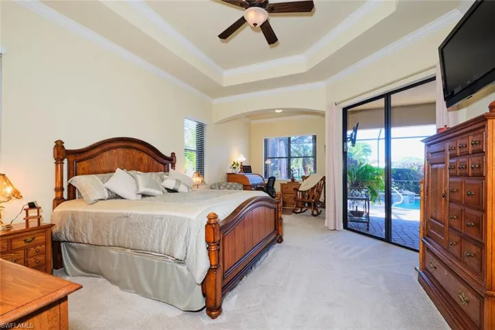 Bedroom featuring access to exterior, ceiling fan, a raised ceiling, light colored carpet, and ornamental molding