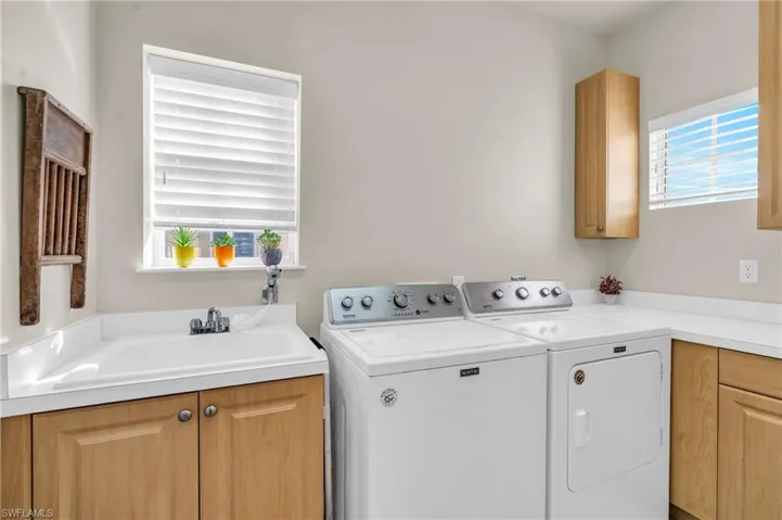 Laundry room featuring sink, plenty of natural light, cabinets, and independent washer and dryer