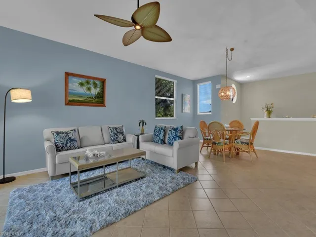 Living area featuring ceramic tile flooring, a ceiling fan, and a light blue accent wall