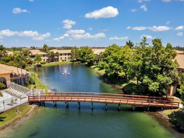 Wood bridge spanning a serene waterway with a central fountain feature