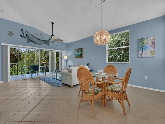 Open-concept living area with vaulted ceilings, large format tile flooring, and a glass sliding door leading to an outdoor space