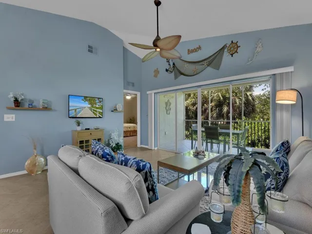 Living area featuring vaulted ceilings, a ceiling fan, and sliding glass doors opening to an outdoor patio