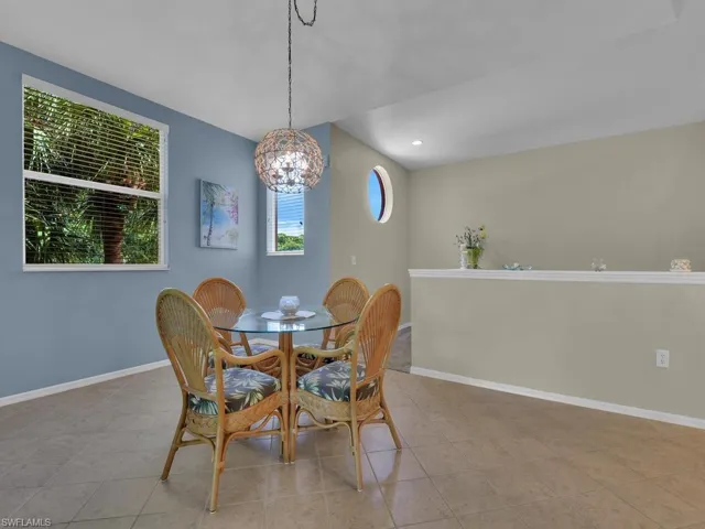 Open-concept dining area featuring tile flooring, a decorative spherical chandelier, and multiple windows including a circular accent window