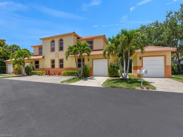 Mediterranean-style exterior, arched windows, stucco finish, attached garages, and established palm trees