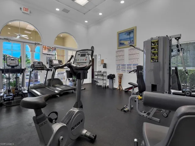 Fitness center featuring recessed lighting, high ceilings, arched windows, and direct access to an outdoor area