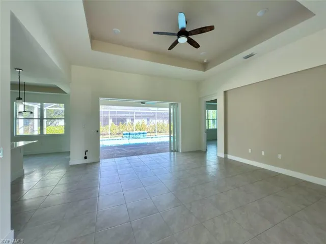 with plenty of natural light, ceiling fan, a tray ceiling, and light tile patterned floors