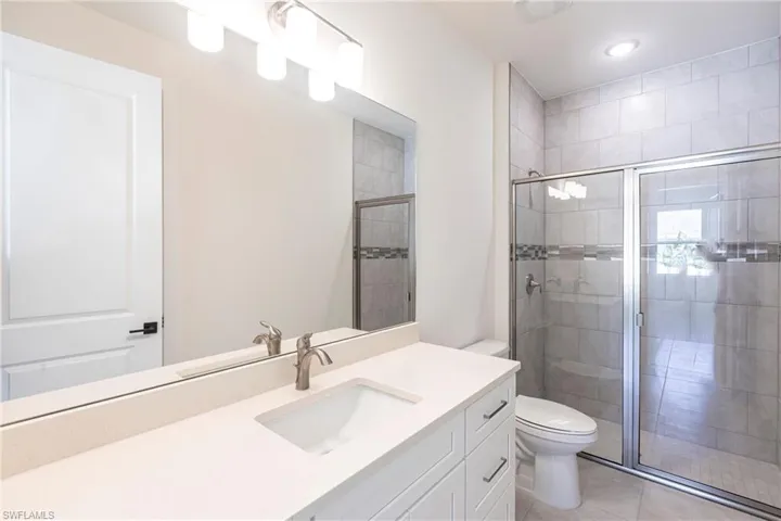 Full bath featuring toilet, a stall shower, tile patterned floors, and vanity