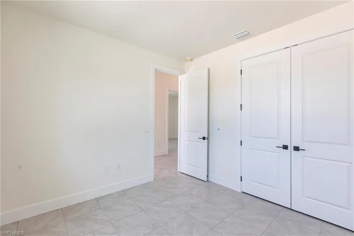 Unfurnished bedroom featuring baseboards, visible vents, and a closet