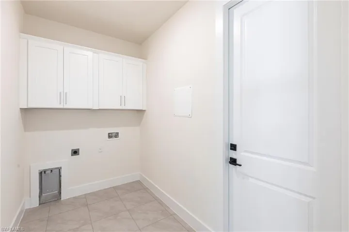 Washroom featuring light tile patterned flooring, hookup for a washing machine, hookup for an electric dryer, baseboards, and cabinet space