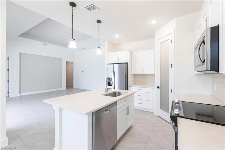 Kitchen with appliances with stainless steel finishes, light countertops, white cabinets, and visible vents