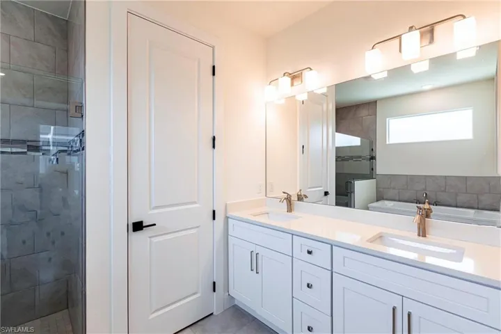 Bathroom featuring double vanity, a sink, a free standing bath, and a walk in shower