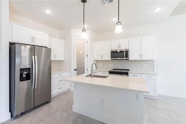 Kitchen featuring stainless steel appliances, white cabinets, light countertops, and a sink