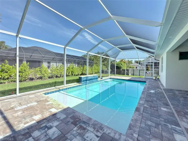 Pool featuring glass enclosure and a patio