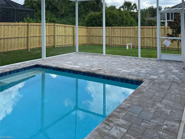 View of pool with a patio, a fenced backyard, and a lanai