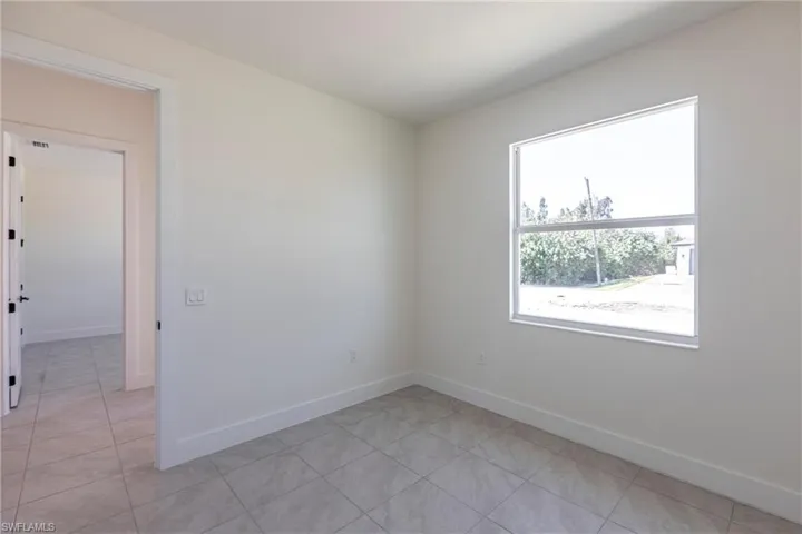 Unfurnished room with light tile patterned floors and baseboards