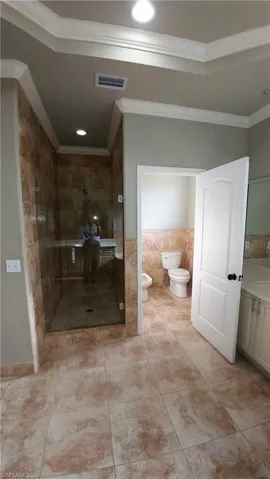 Bathroom with a bidet, crown molding, a stall shower, tile walls, and vanity