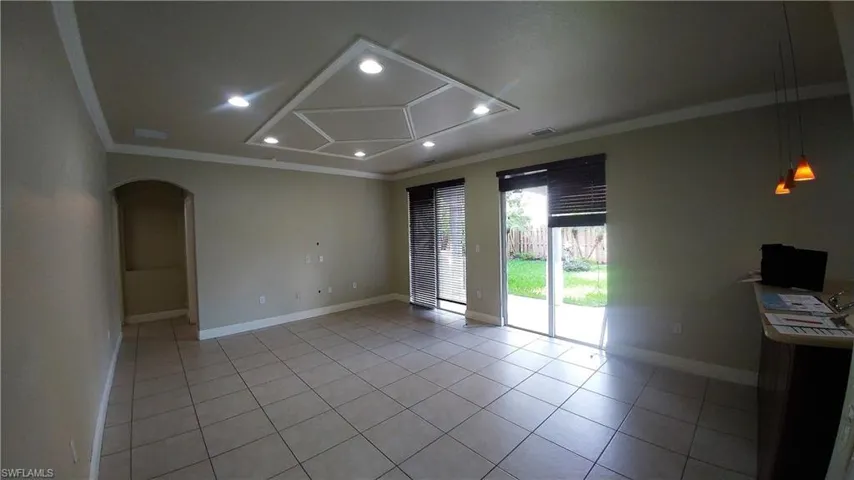 Unfurnished room with crown molding, arched walkways, light tile patterned flooring, and recessed lighting