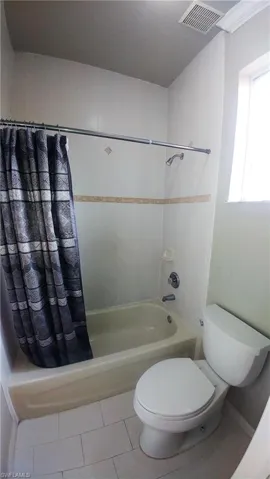 Bathroom featuring shower / tub combo with curtain and tile patterned floors