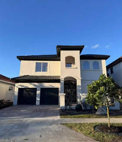 Mediterranean / spanish-style house with a garage, driveway, stucco siding, and a tiled roof