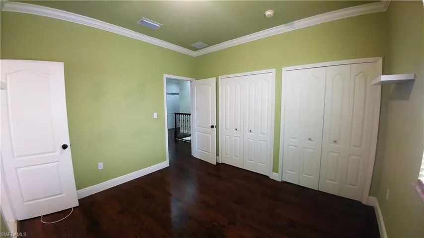 Bedroom featuring w/2 custom closets, wood-style floors, and ornamental molding