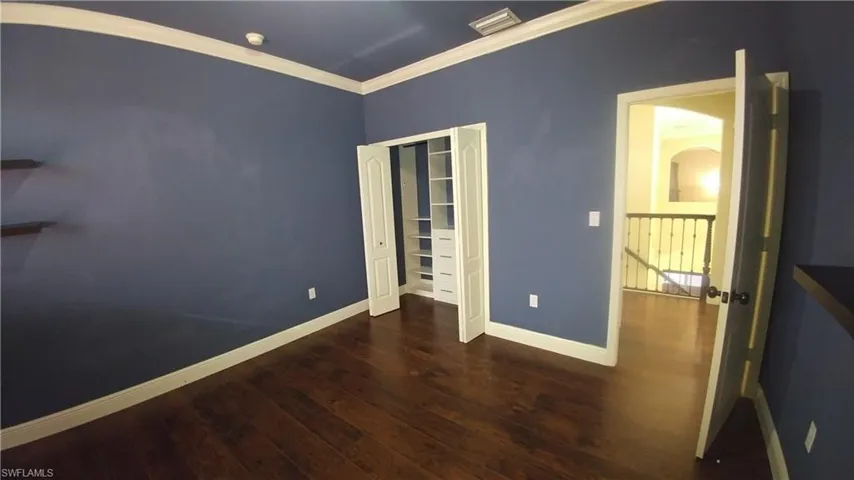 Bedroom features custom closet, wood floors, & crown molding